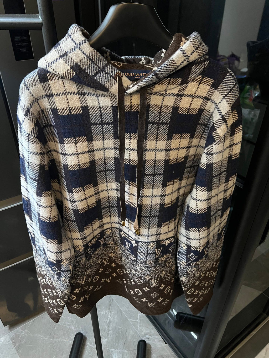 Hooded sweatshirt with cream-and-navy plaid front, brown monogram hem, drawstring hood
