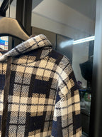 Plaid hoodie sleeve with cream-and-navy checks and textured brown monogram panel