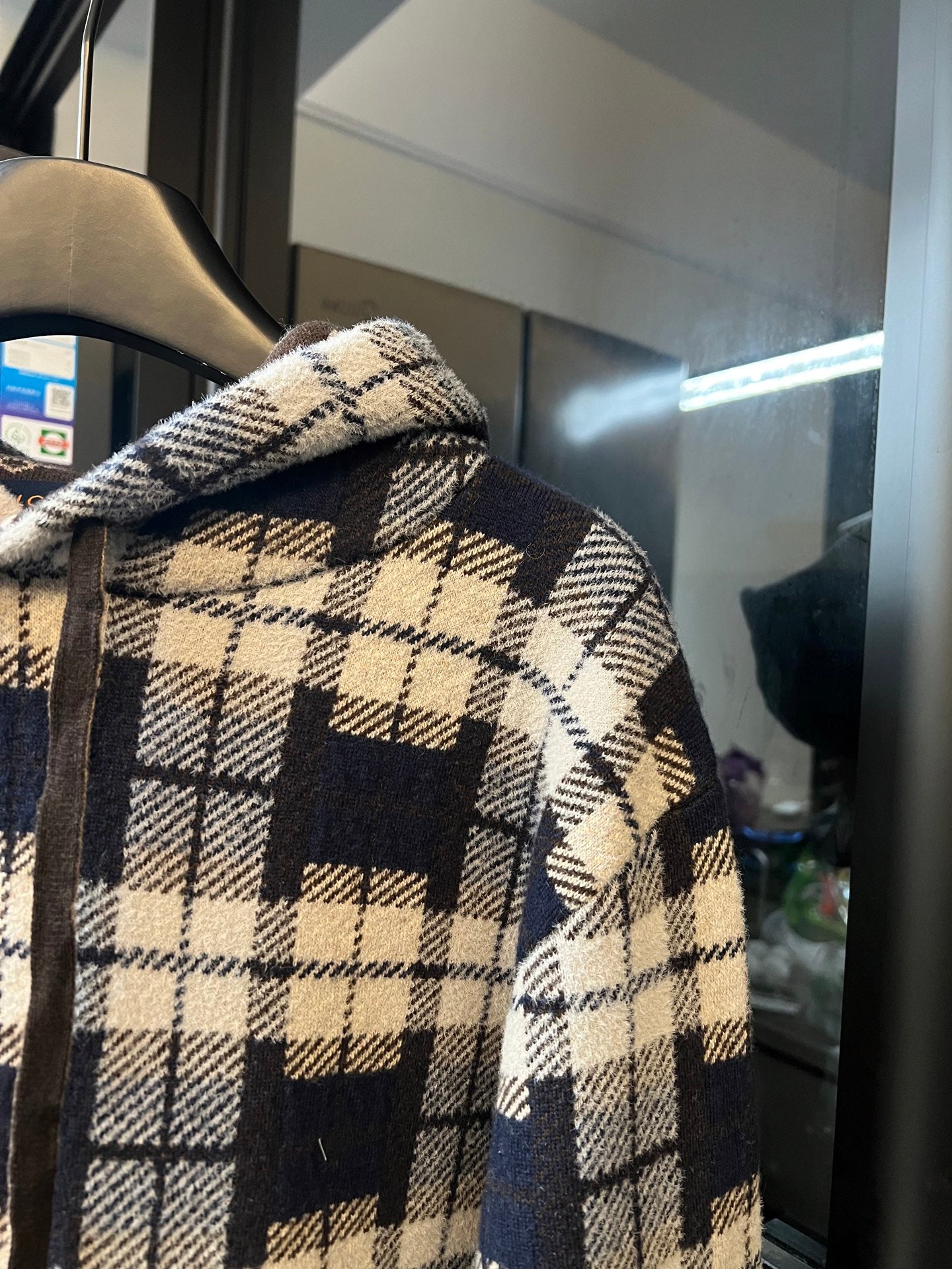 Plaid hoodie sleeve with cream-and-navy checks and textured brown monogram panel