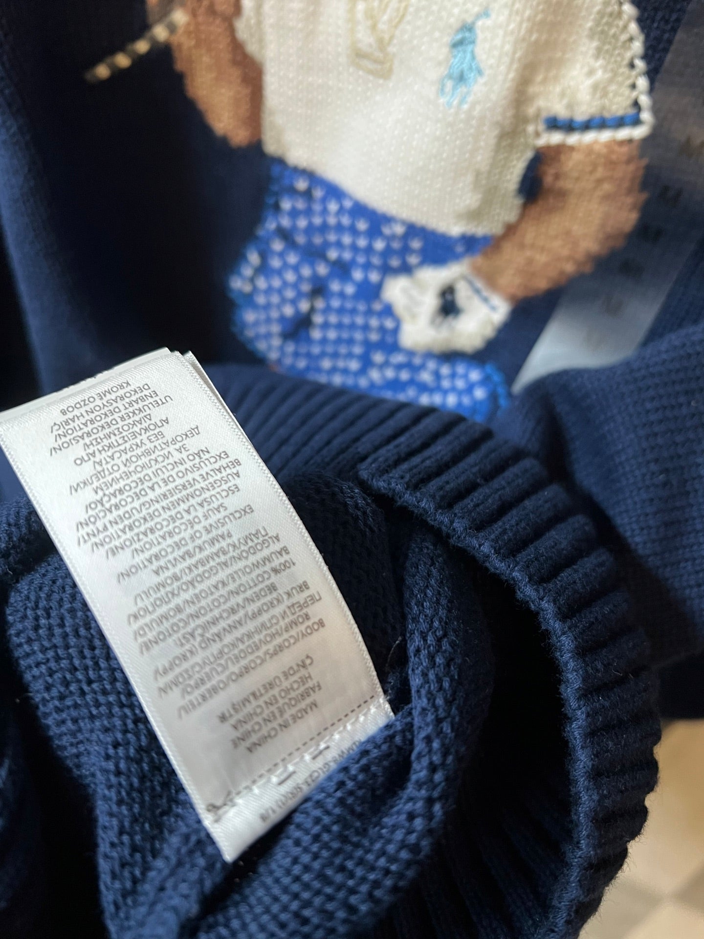 Dark blue knit sweater care label tag on inside neckline area