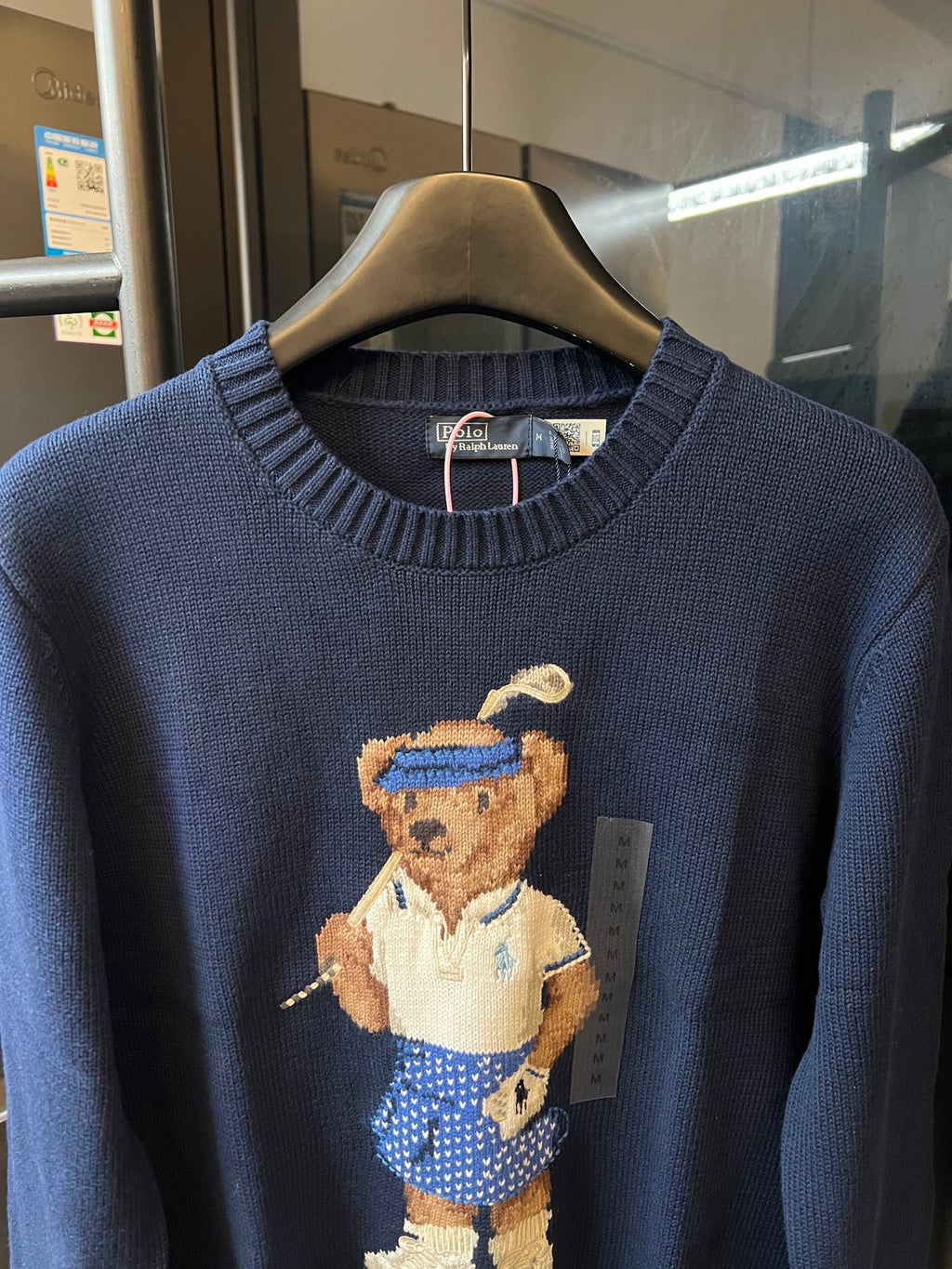 Dark blue knit sweater with embroidered bear character, crew neck close-up