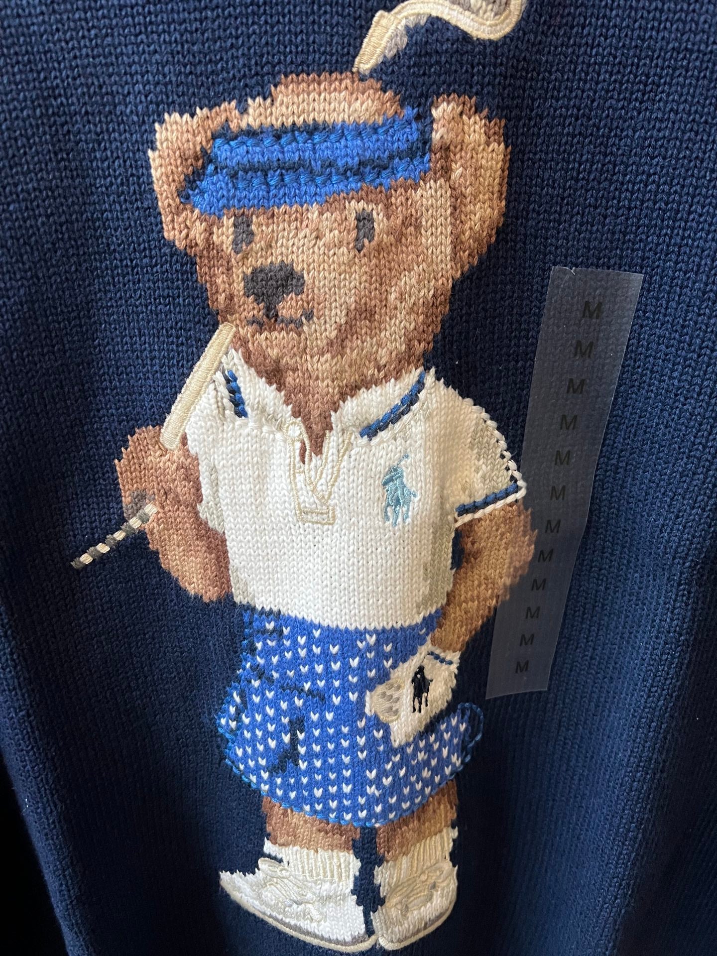 Dark blue knit sweater with close-up of embroidered bear character graphic
