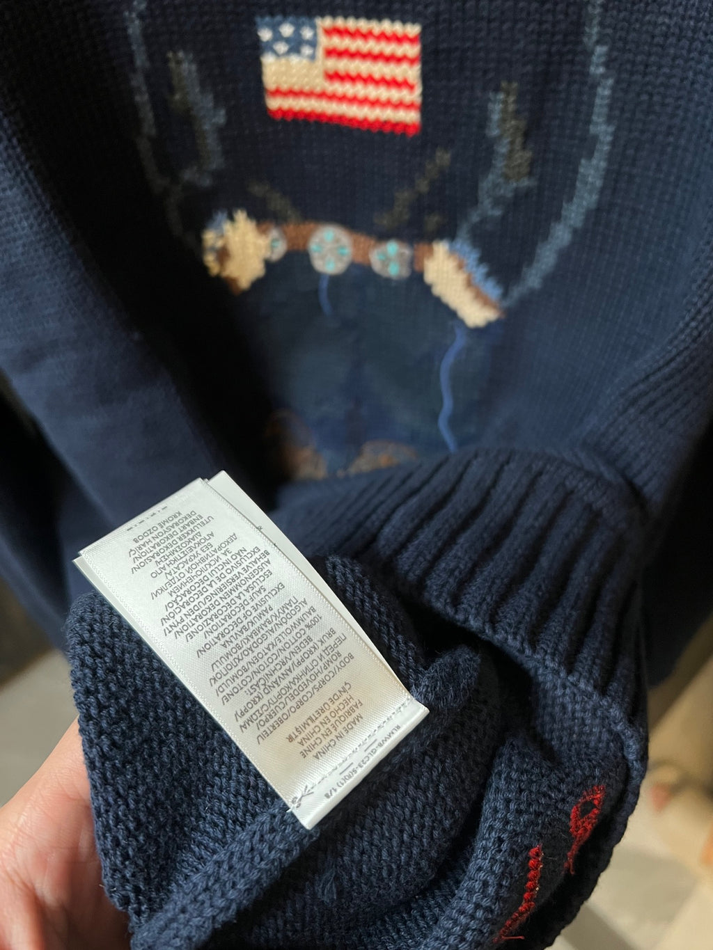 Navy knit sweater sleeve with care label tag near the hem