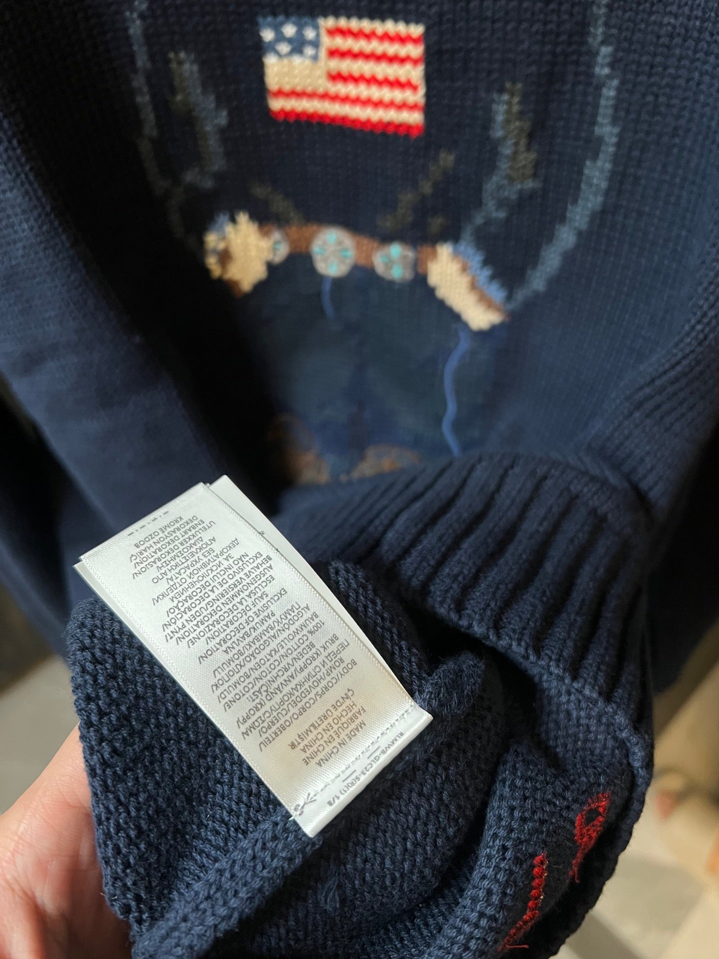 Navy knit sweater sleeve with care label tag near the hem