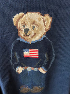 Close-up navy knit sweater showing teddy bear face and American flag