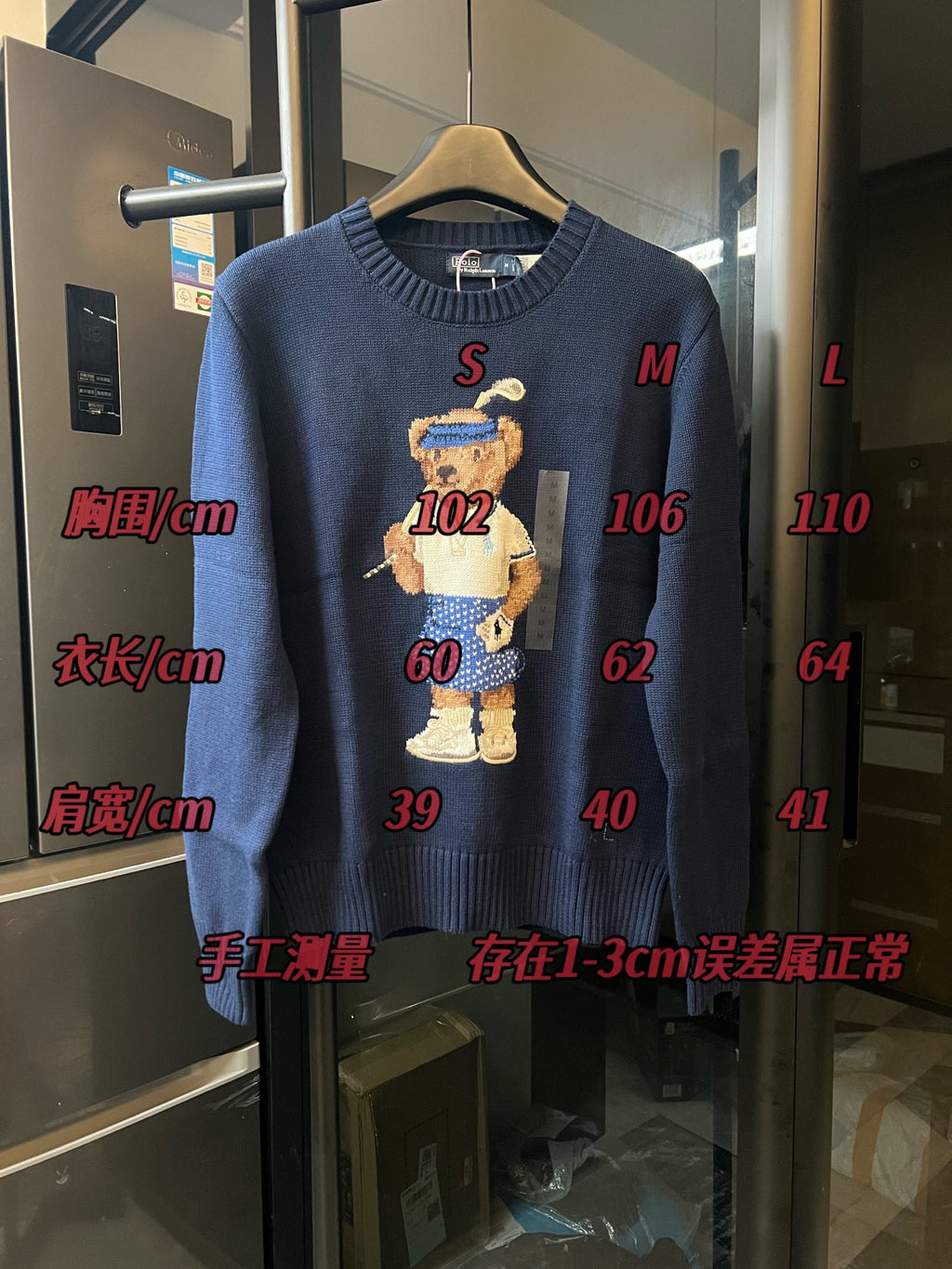 Dark blue knit sweater with embroidered bear character and size measurements overlay