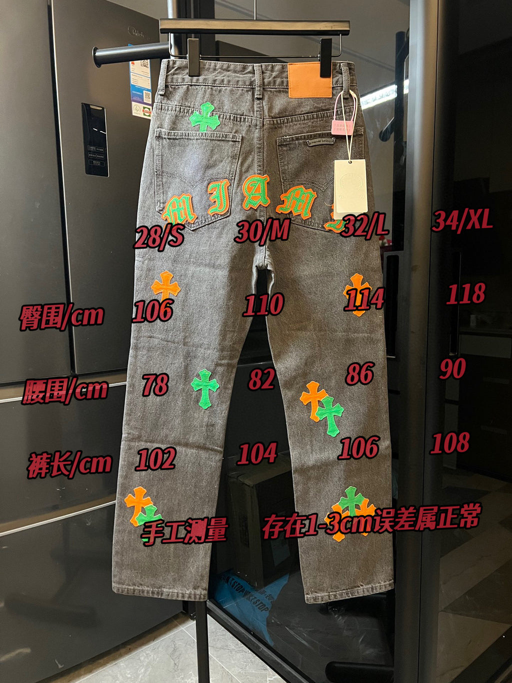 Light gray denim pants on display with size markings and colorful cross patches