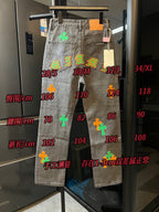 Light gray denim pants on display with size markings and colorful cross patches