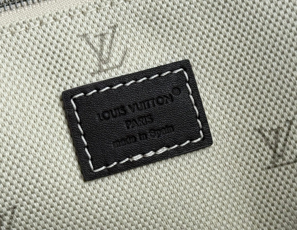 Beige textured bag with black leather logo patch and white stitching