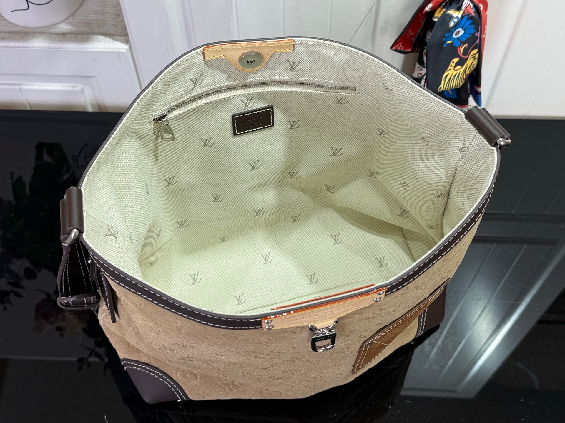 Beige Louis Vuitton monogram bucket-style bag with dark zipper and light fabric lining