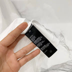 White Amiri T-shirt neck label and care tag held in hand