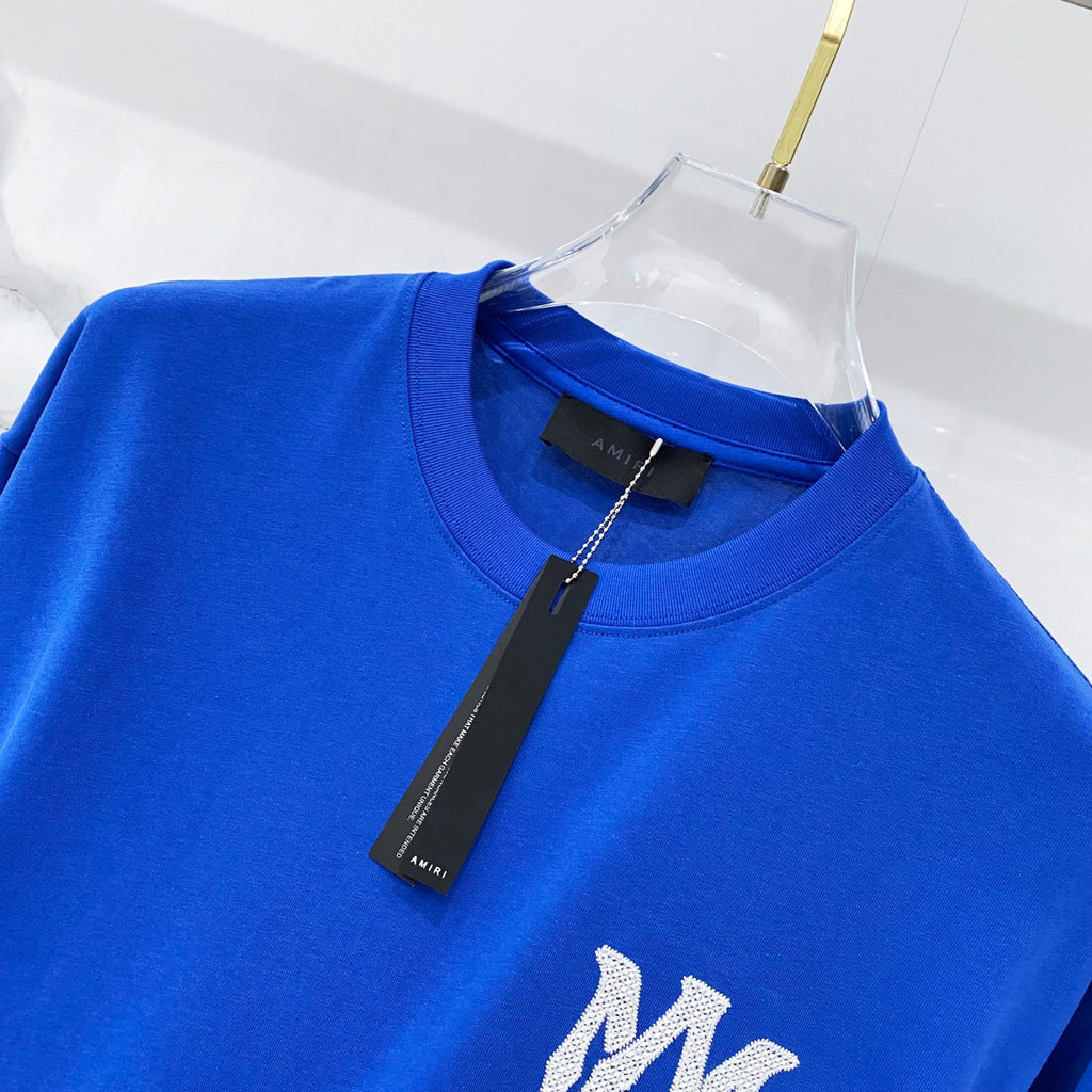 Blue crewneck T-shirt on hanger, with white monogram detail at chest