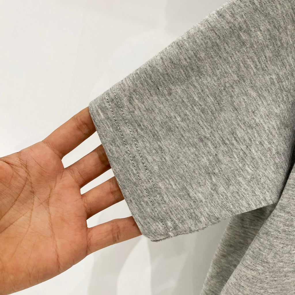 Amiri heather gray T-shirt fabric close-up held by hand