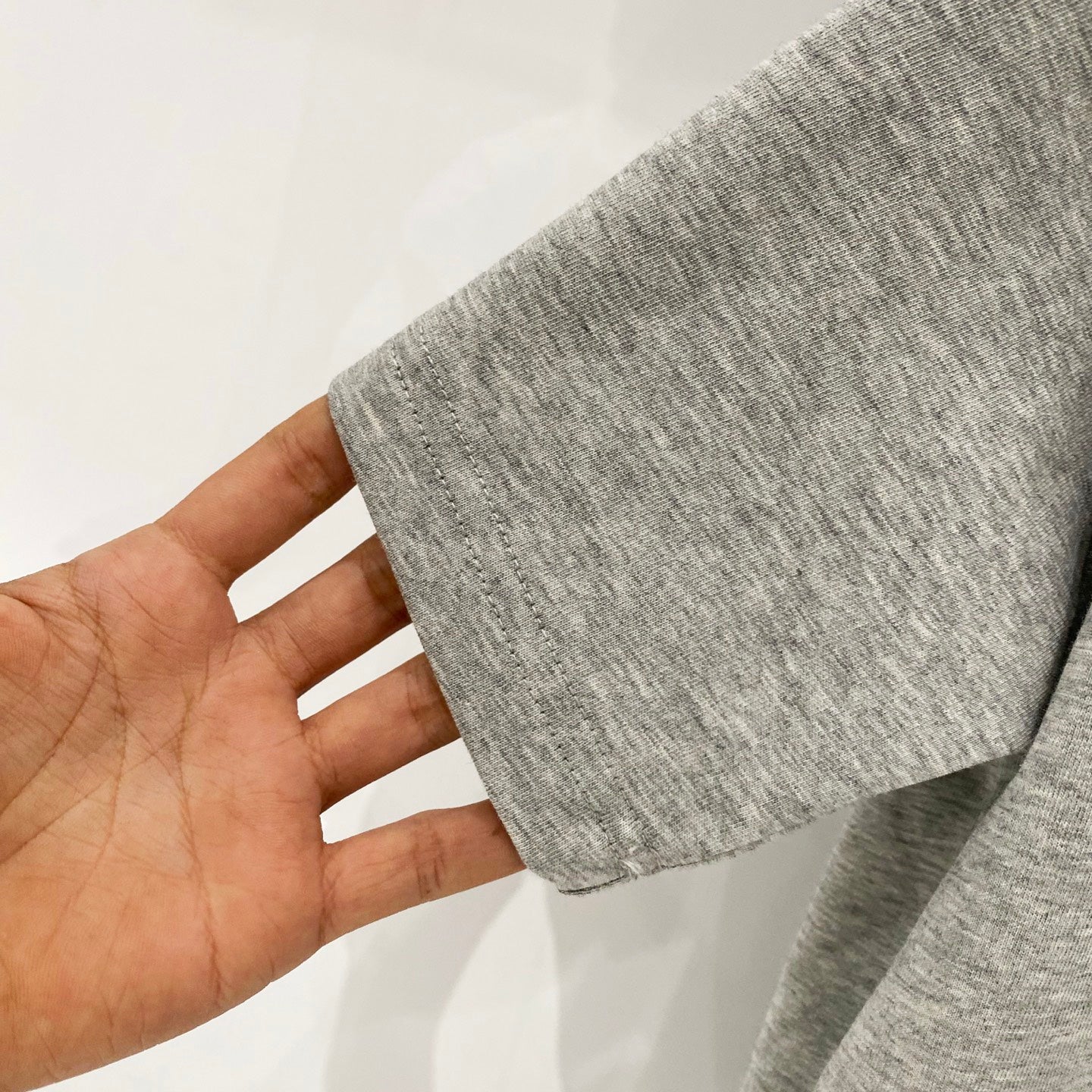 Amiri heather gray T-shirt fabric close-up held by hand