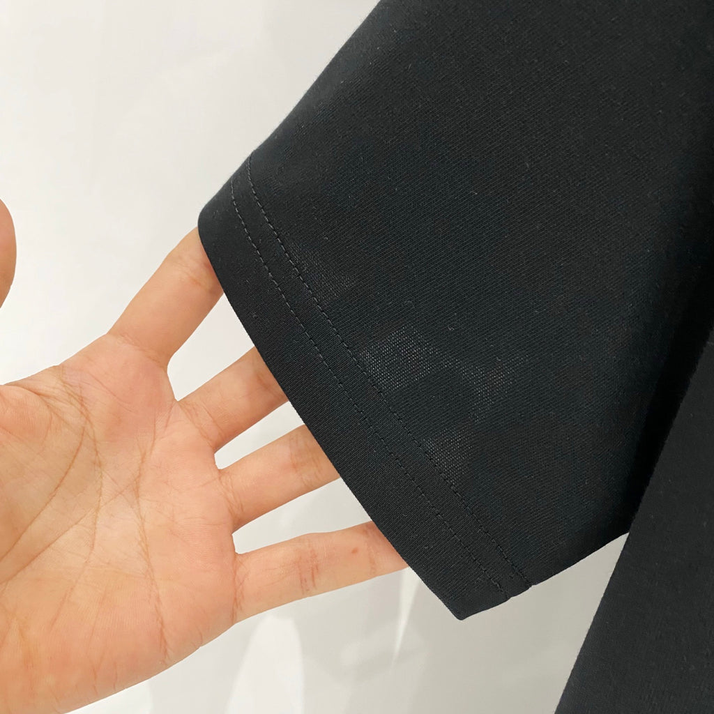 Black T-shirt hem and side seam held in hand