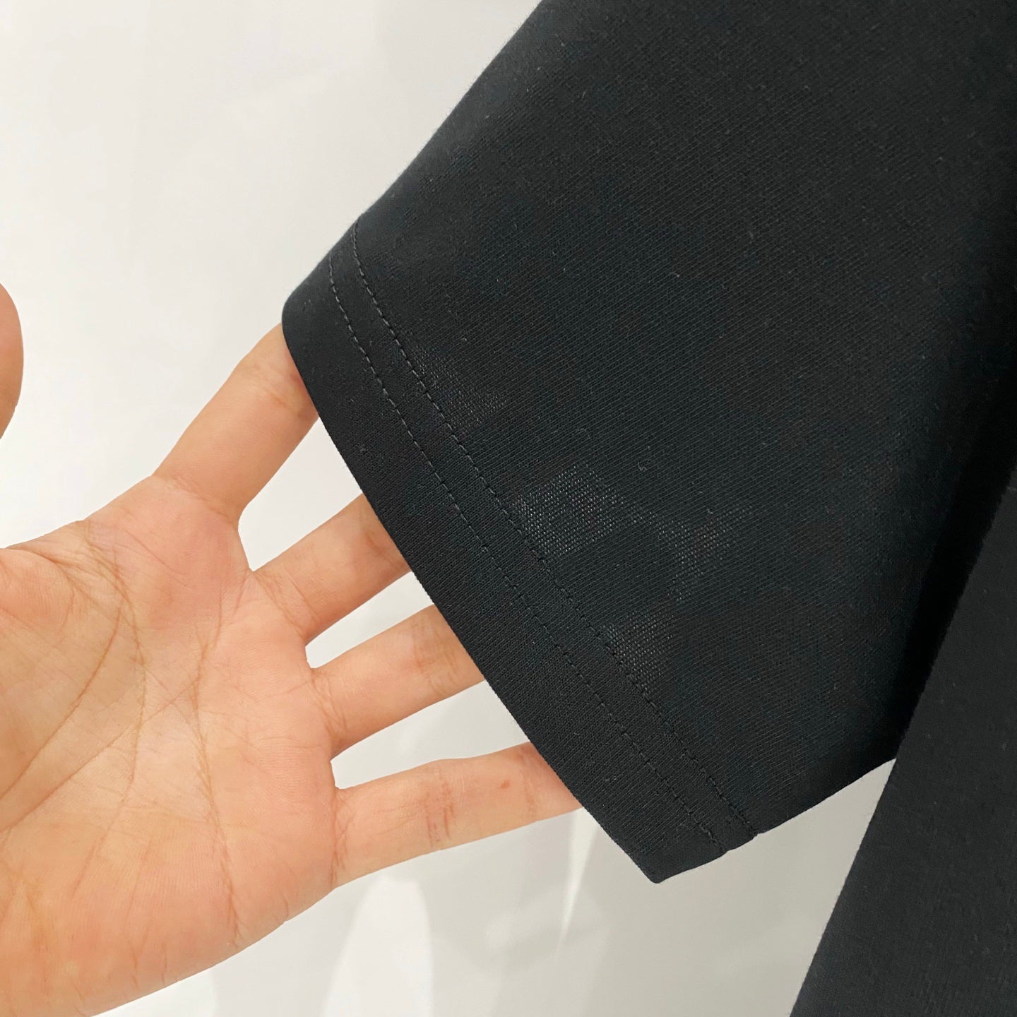 Black T-shirt hem and side seam held in hand