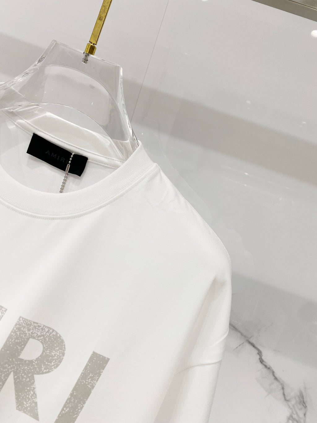 White crewneck T-shirt close-up with AMIRI logo detail and neckline tag
