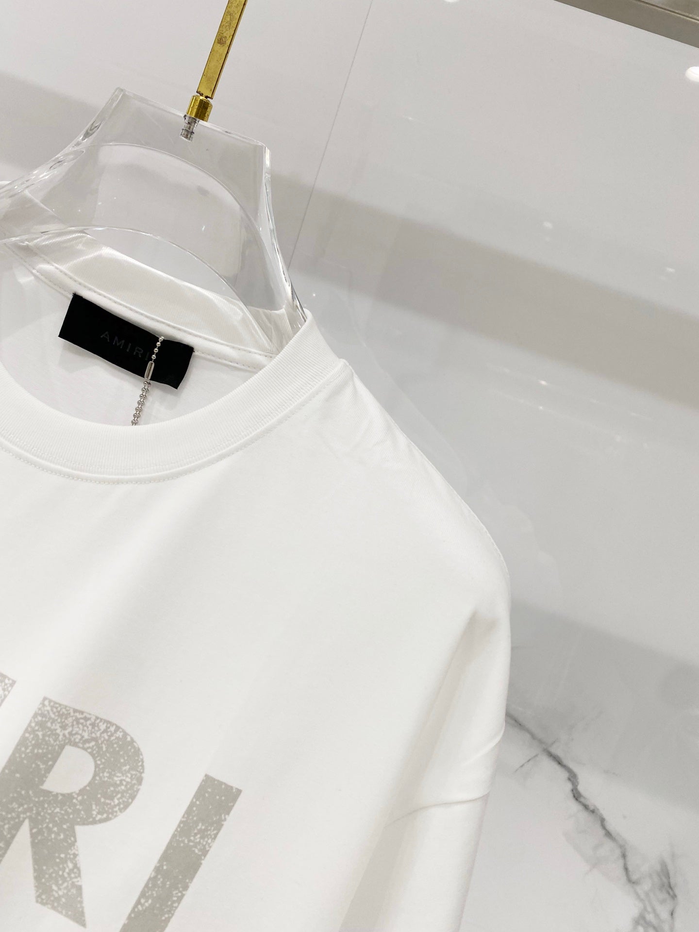 White crewneck T-shirt close-up with AMIRI logo detail and neckline tag