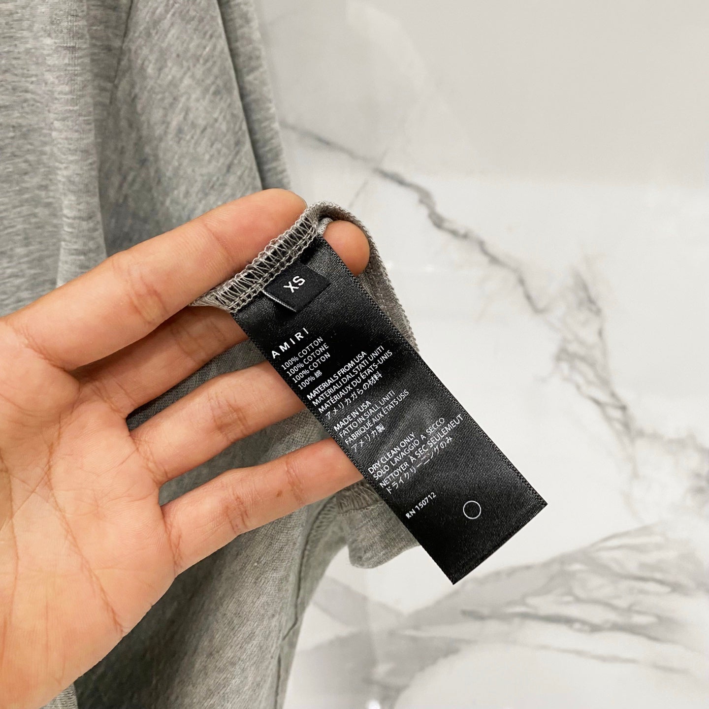 Amiri T-shirt care label at side seam on heather gray fabric