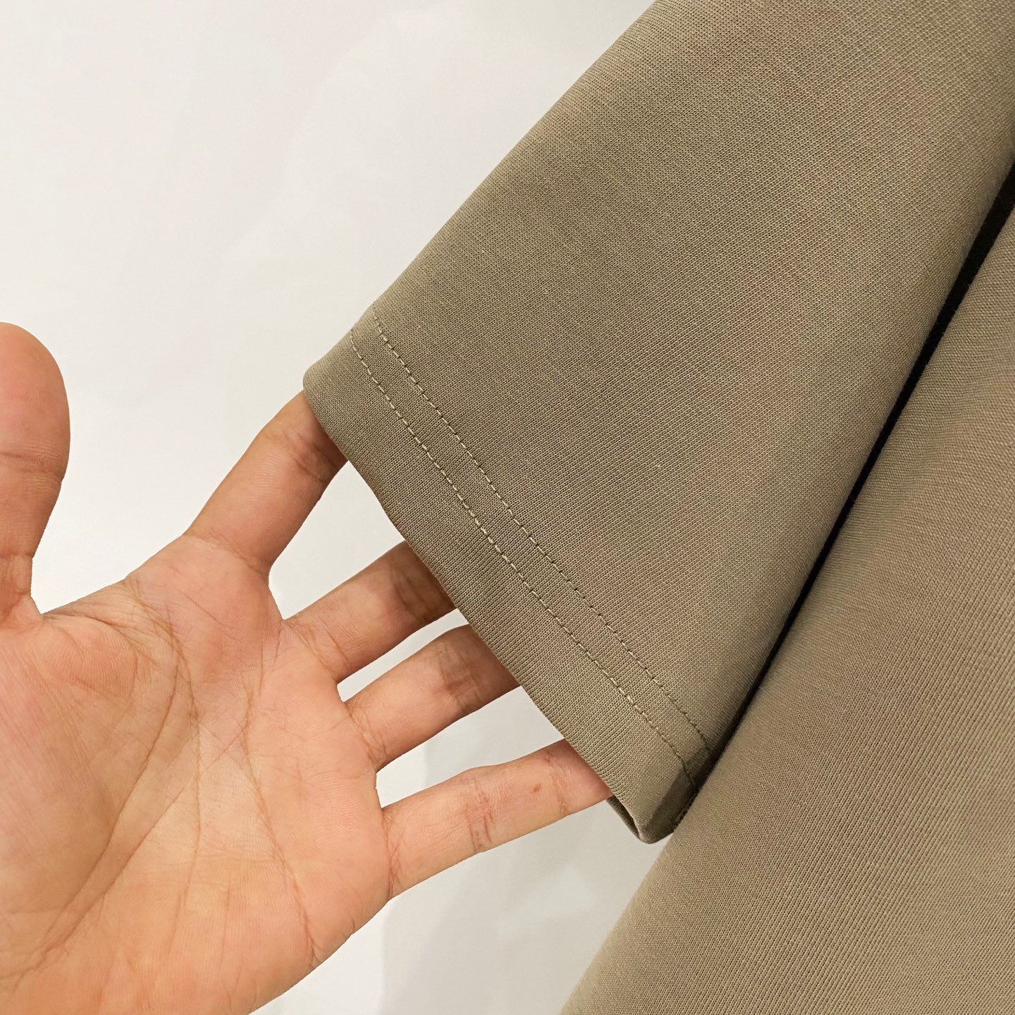 Olive T-shirt sleeve hem with visible double stitching and fabric weave