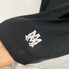 Black Amiri T-shirt sleeve with small cream emblem graphic near cuff
