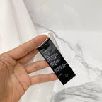 White T-shirt interior with black size label tag held up for viewing.