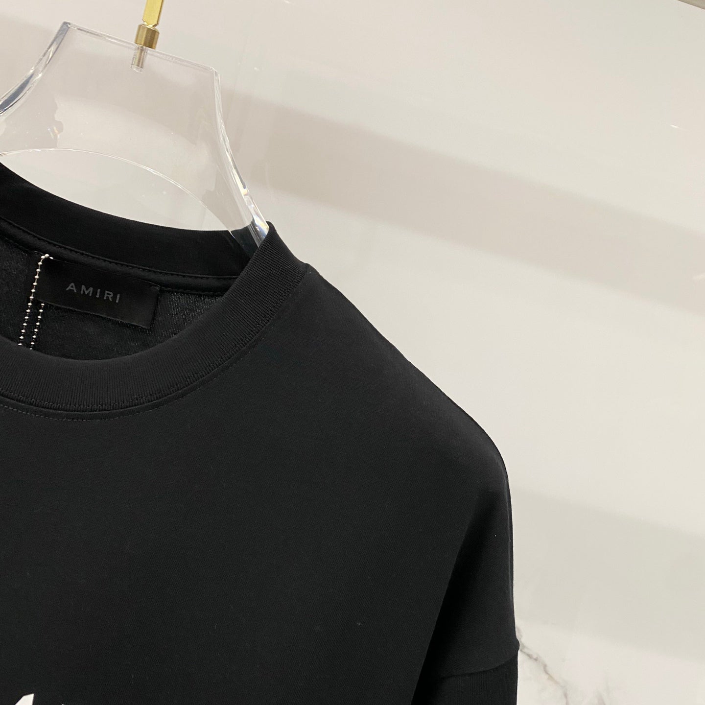 Black crewneck T-shirt neckline with AMIRI label at the collar