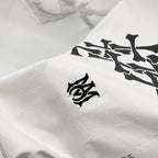Amiri white T-shirt fabric close-up with small black logo emblem