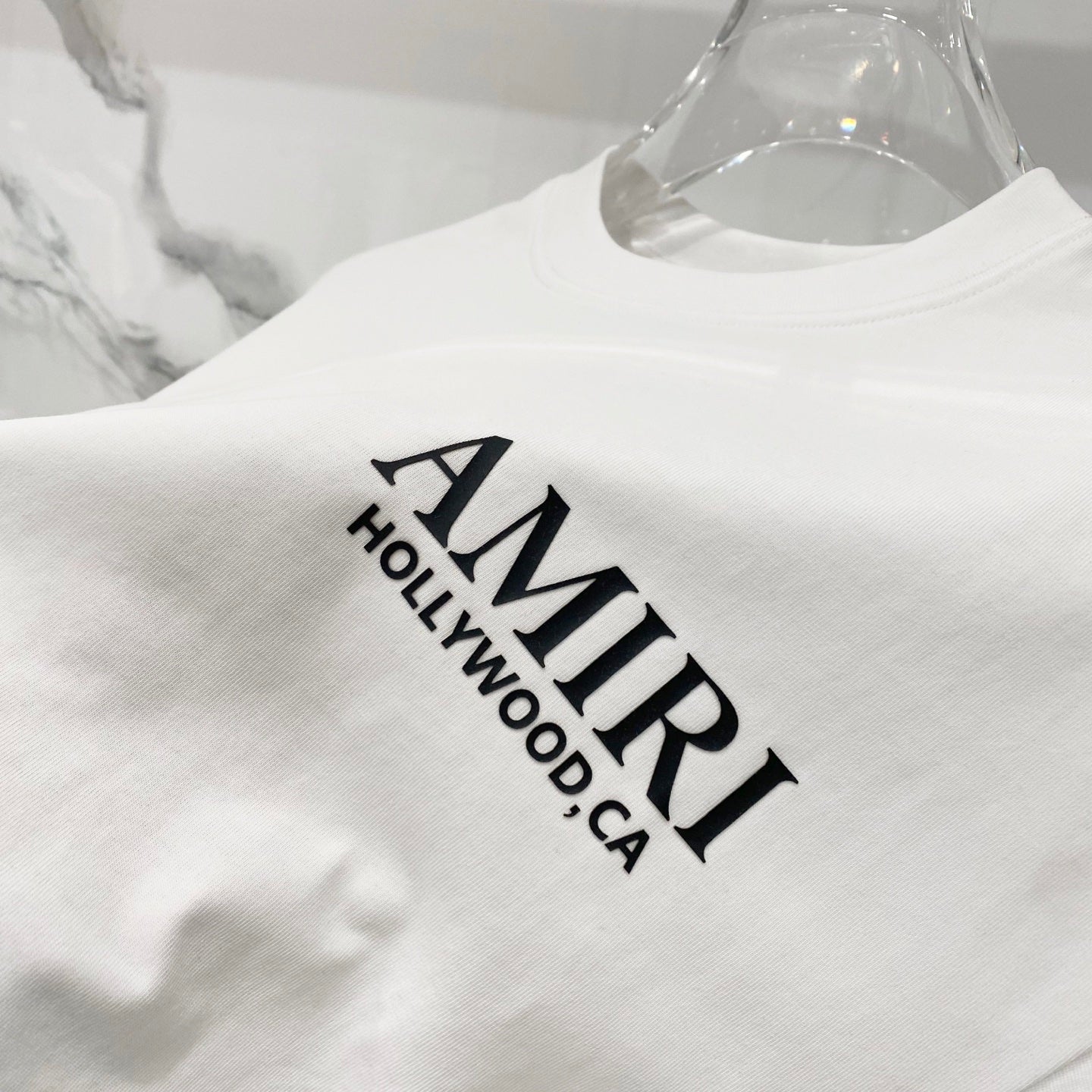 Amiri white T-shirt close-up of AMIRI Hollywood CA logo print