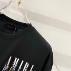 Black T-shirt with partial AMIRI logo print in white and multicolor streaks