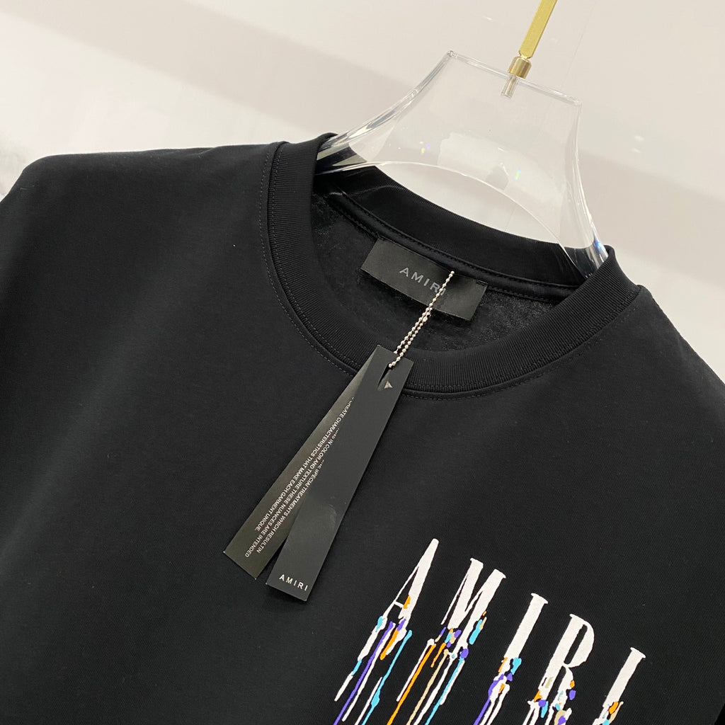 Black crewneck T-shirt with hanging brand tag and AMIRI logo graphic