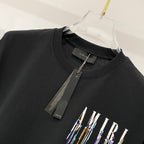 Black crewneck T-shirt with hanging brand tag and AMIRI logo graphic