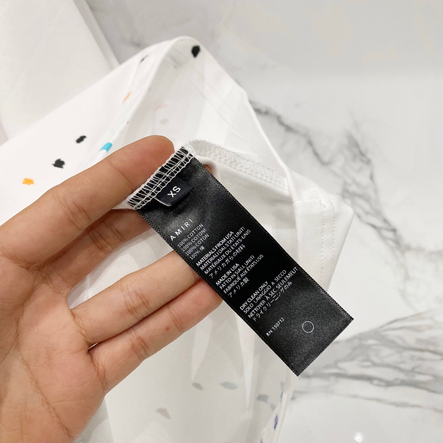 White T-shirt care label tag held in hand