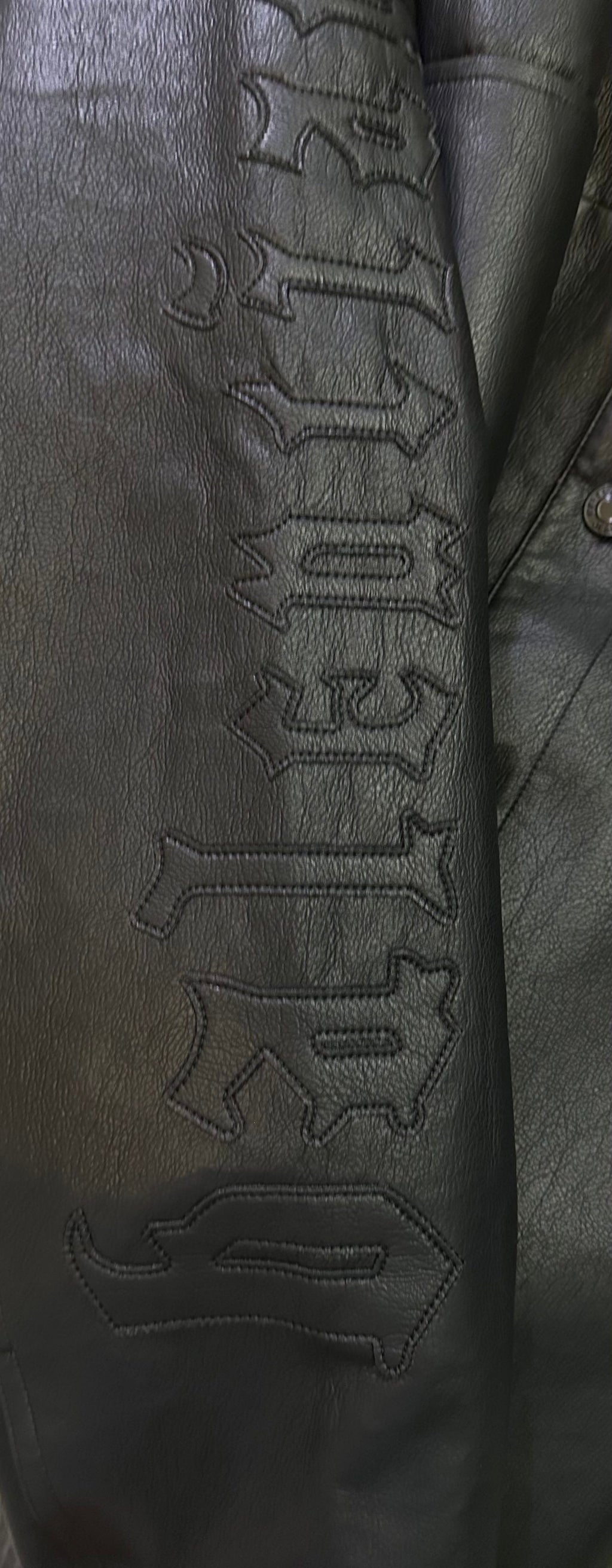 Balenciaga long coat sleeve close-up with embossed lettering on dark leather-look fabric