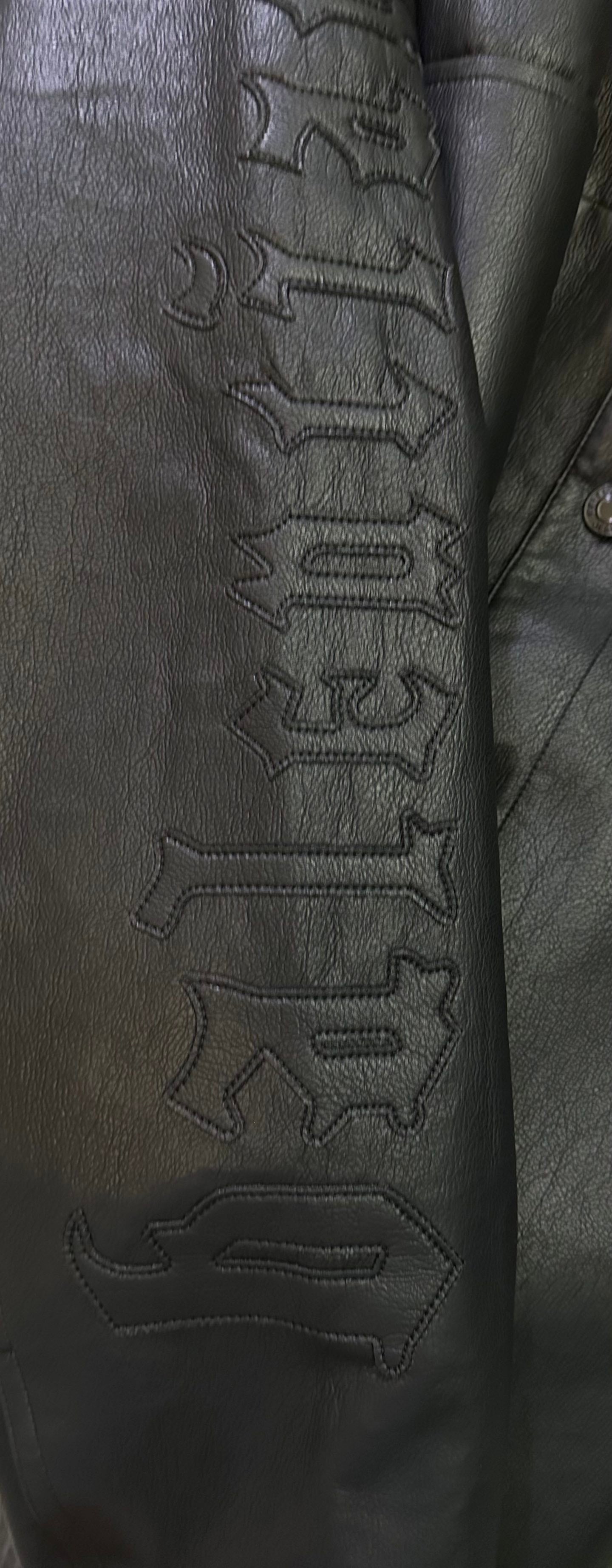 Balenciaga long coat sleeve close-up with embossed lettering on dark leather-look fabric