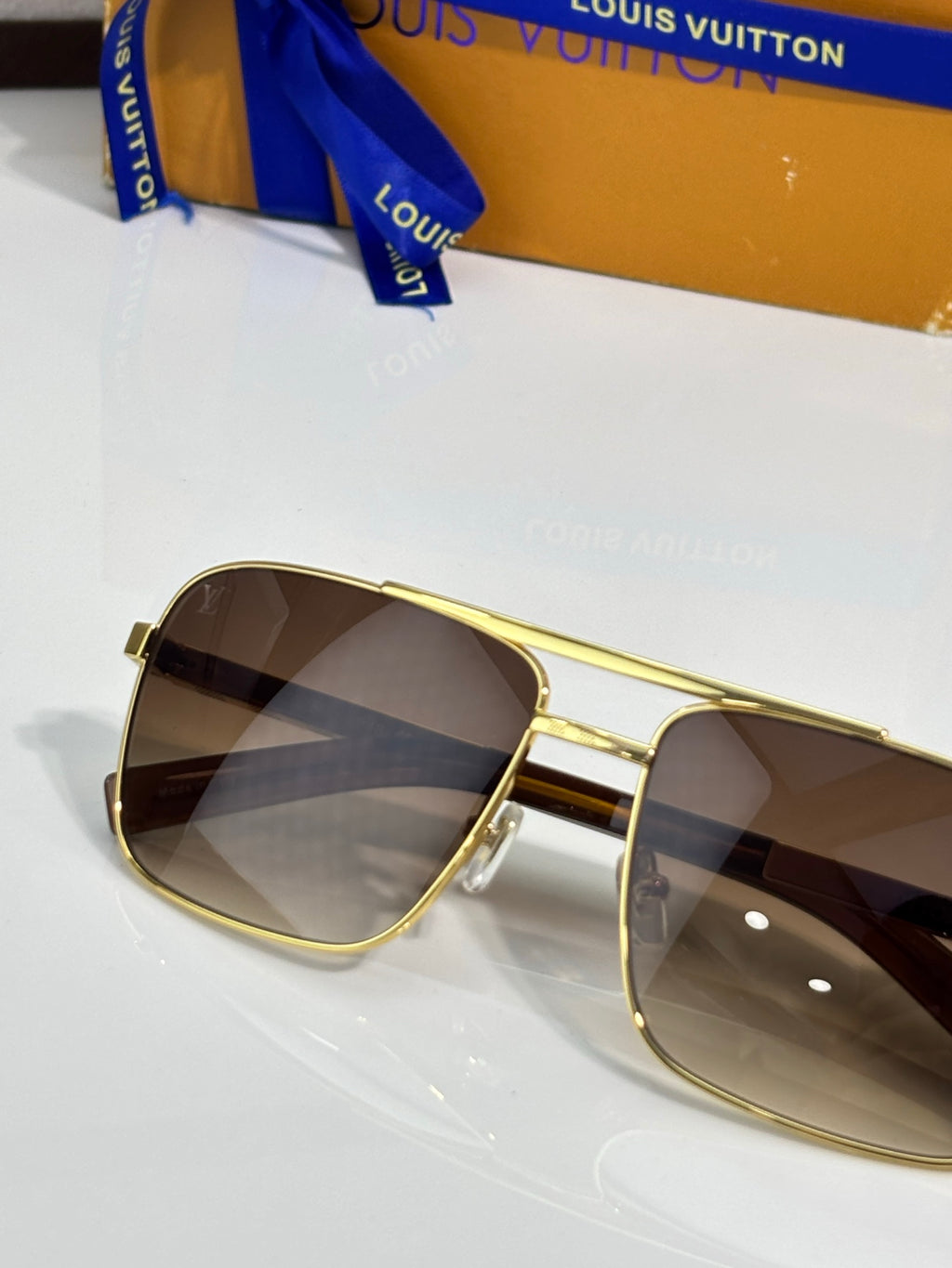 Louis Vuitton gold sunglasses close-up, dark tinted lenses and hinge detail