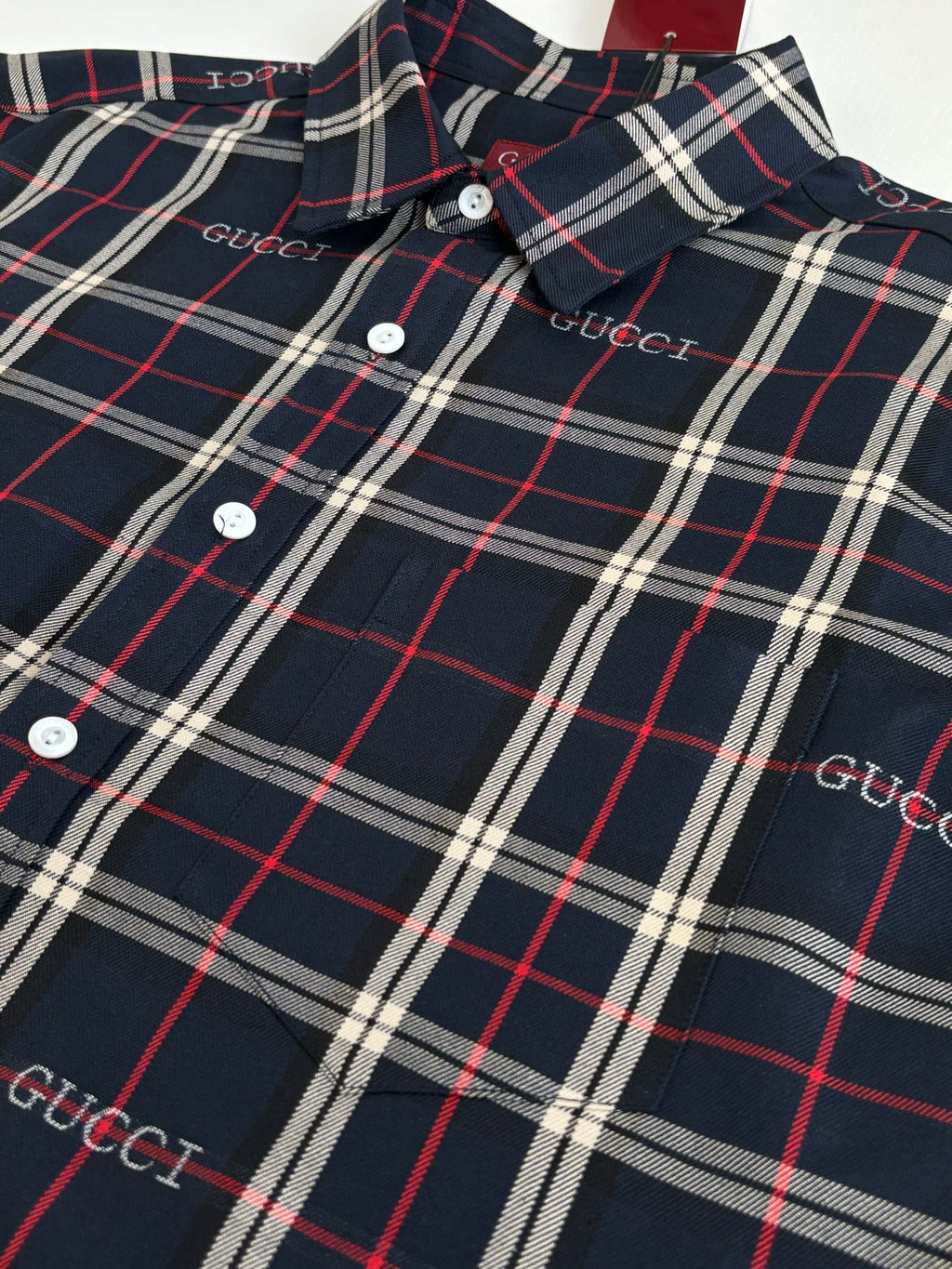 Gucci long-sleeve plaid shirt close-up with buttons and collar, dark navy and red/white lines