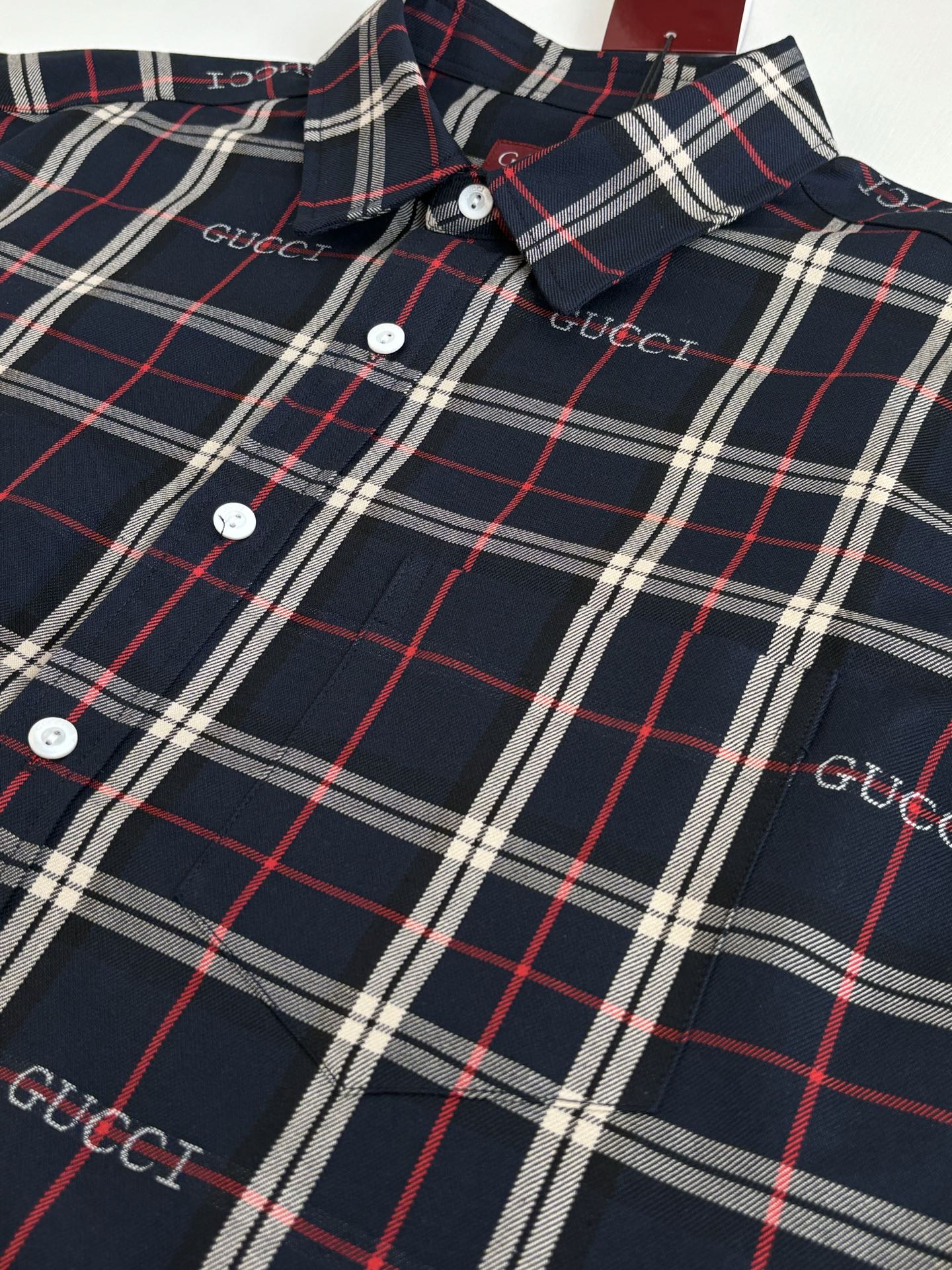 Gucci long-sleeve plaid shirt close-up with buttons and collar, dark navy and red/white lines