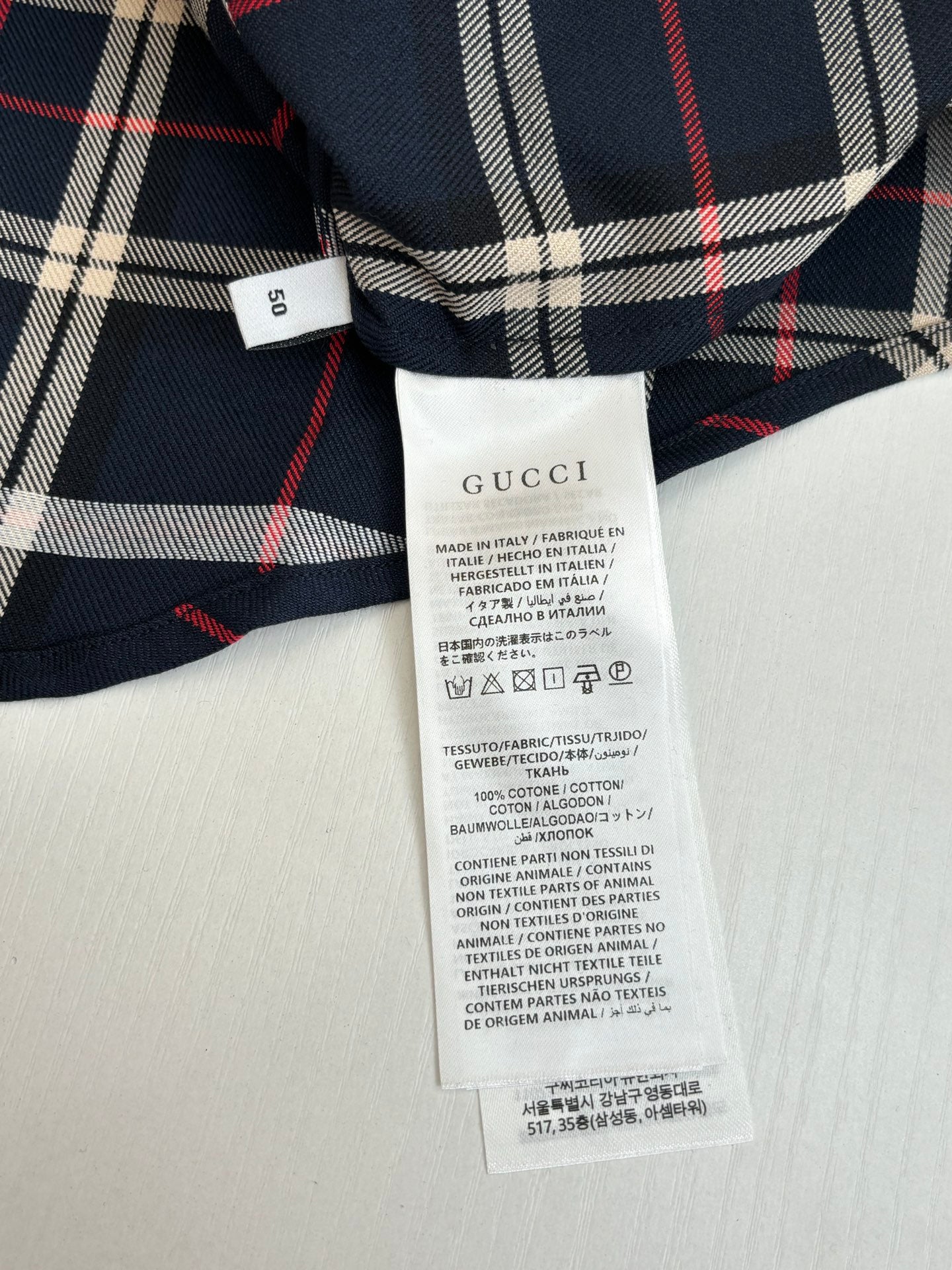 Gucci shirt care label tag on plaid interior, white fabric label with text