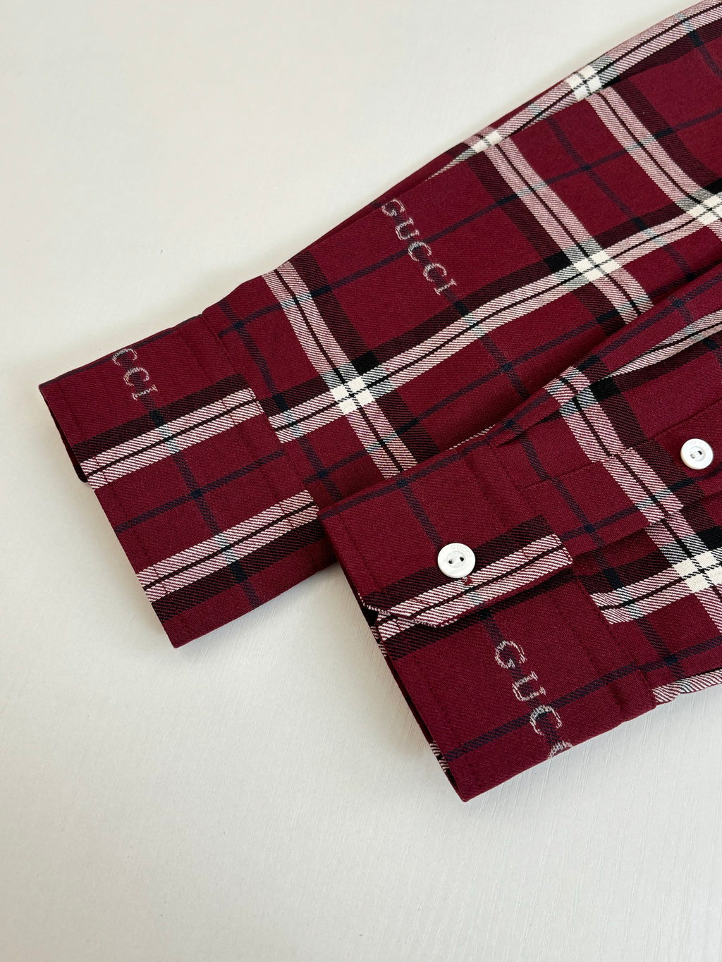 Red plaid long-sleeve shirt cuff with two white buttons