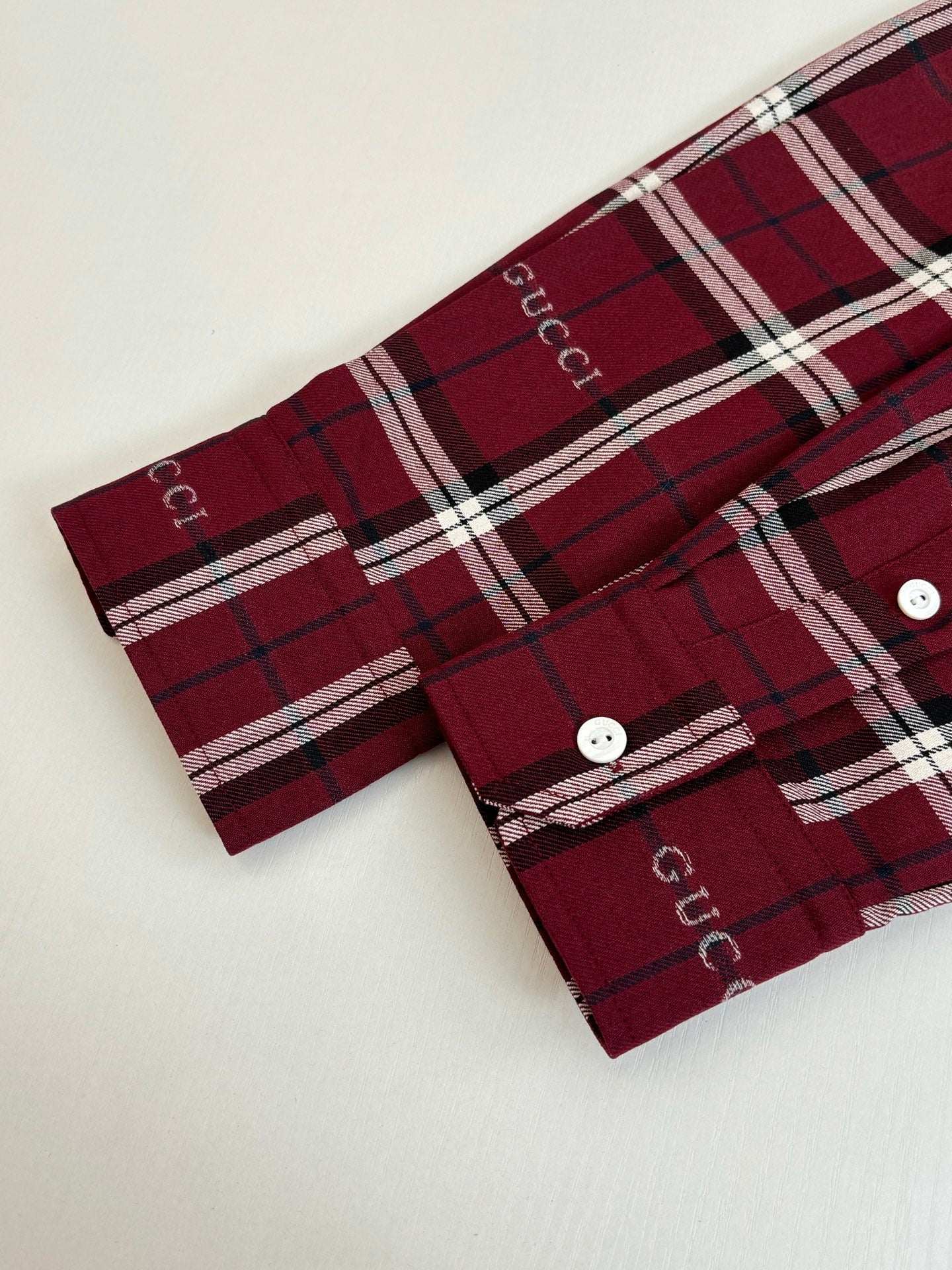 Red plaid long-sleeve shirt cuff with two white buttons