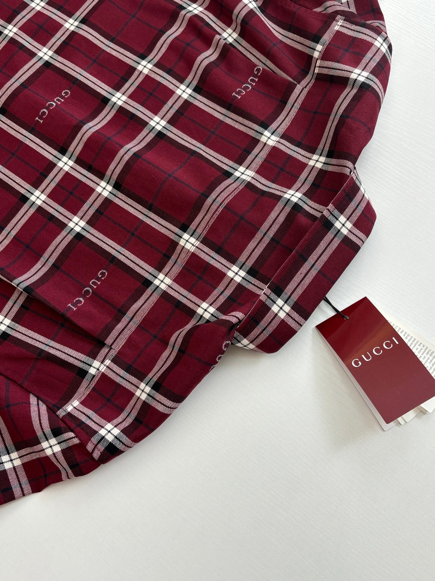 Red plaid long-sleeve shirt with white trim and brand tag detail