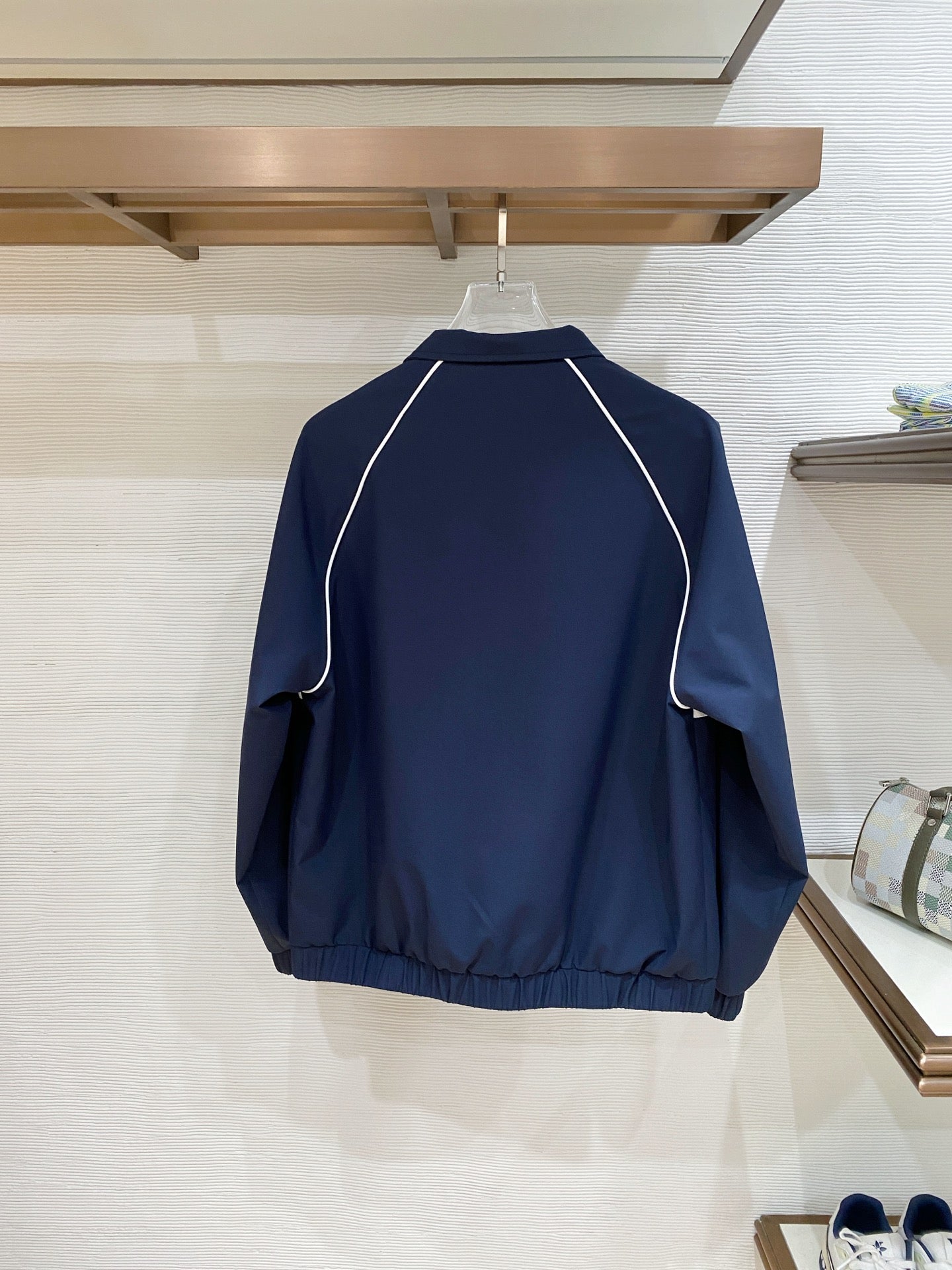 Back of dark navy zip jacket with white contrast piping