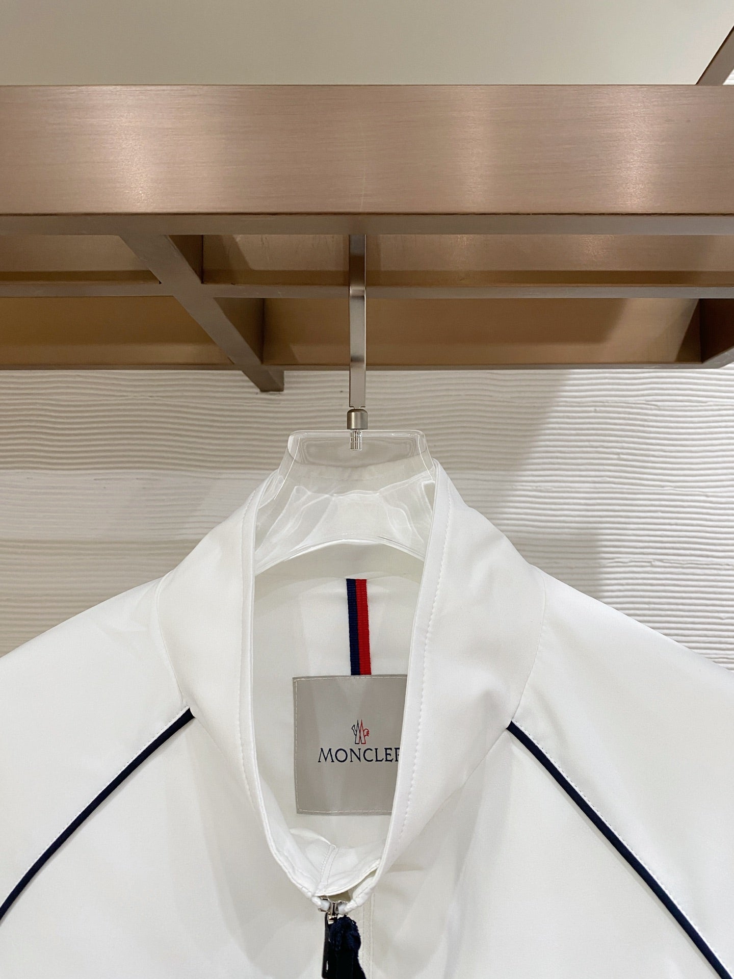 White hooded long jacket with central logo patch and navy piping