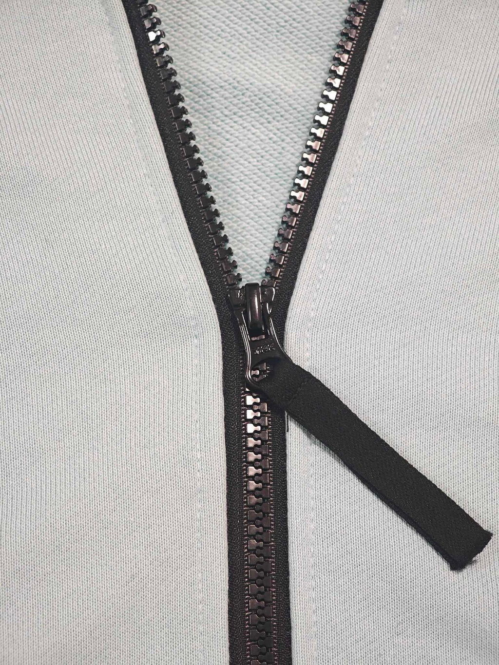 Stone Island light blue zip-up hoodie close-up of black zipper and pull tab