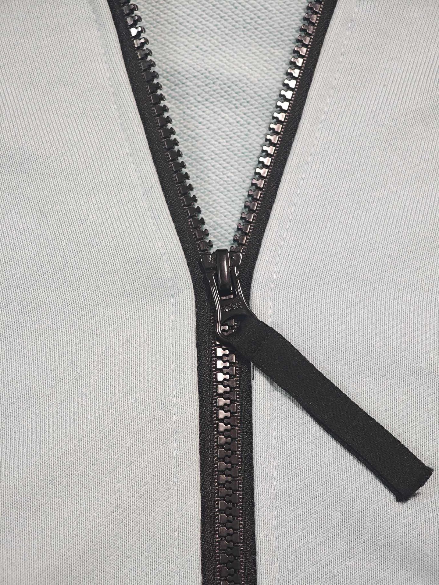 Stone Island light blue zip-up hoodie close-up of black zipper and pull tab