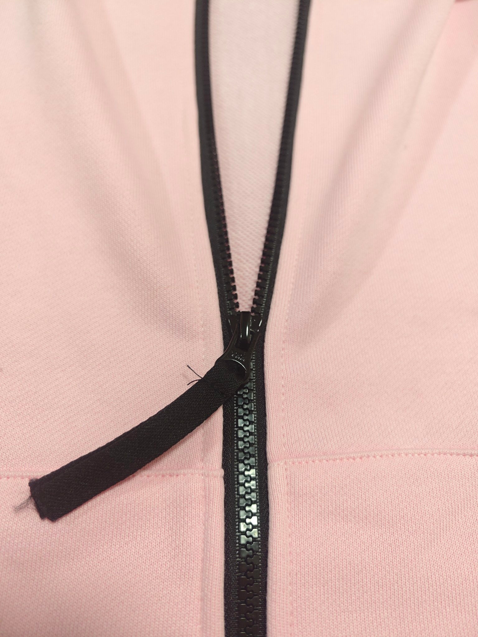 Pink hoodie front panel with black zipper and zip pull