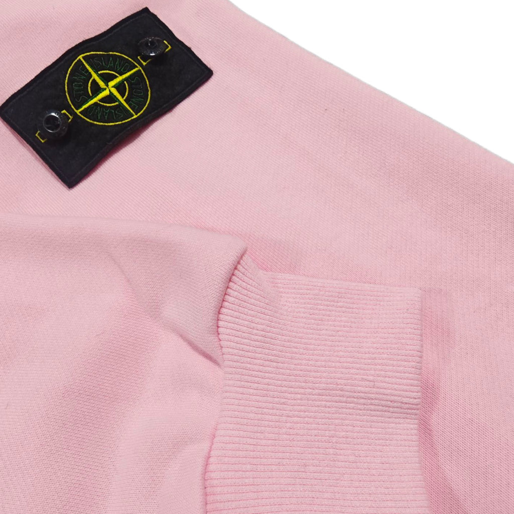 Pink hoodie sleeve cuff with black fabric patch and yellow Stone Island emblem