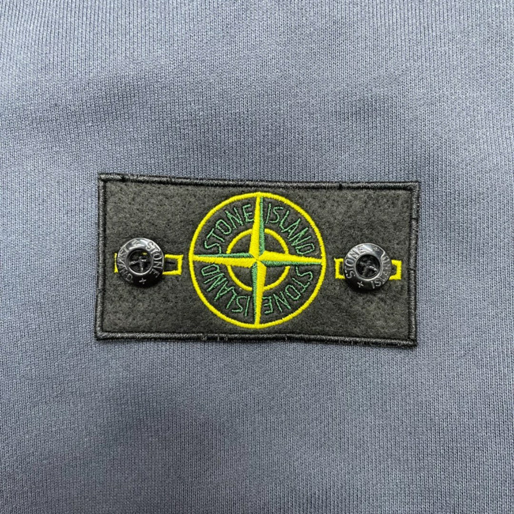 Stone Island logo patch with yellow circular emblem on dark fabric