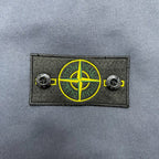 Stone Island logo patch with yellow circular emblem on dark fabric